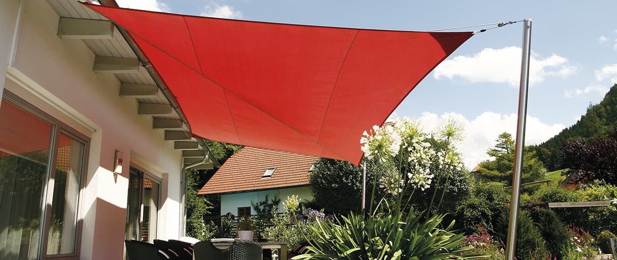 Rotes Sonnensegel über einer Terrasse mit Bepflanzung