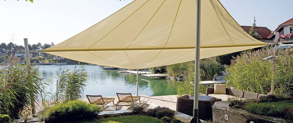 Aufrollbares Sonnensegel in Sandfarbe über einer Terrasse am Wasser